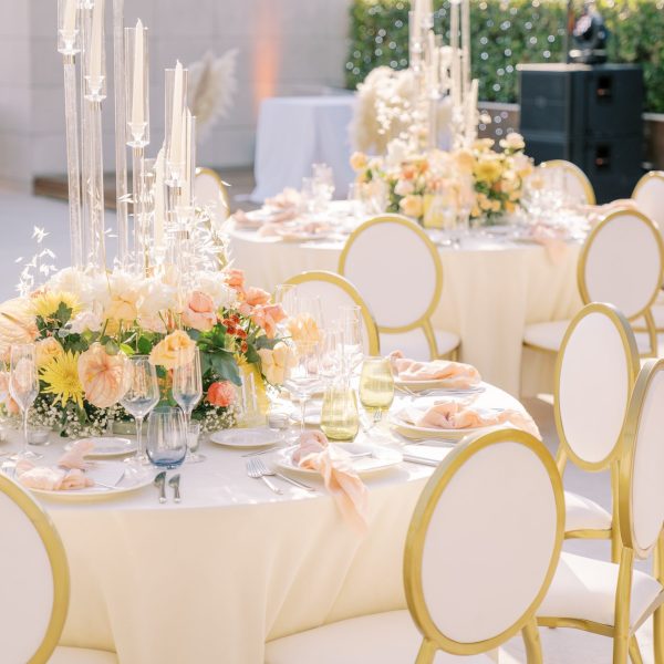 A beautifully arranged wedding reception featuring elegant white tablecloths and gold chairs, creating a festive atmosphere.