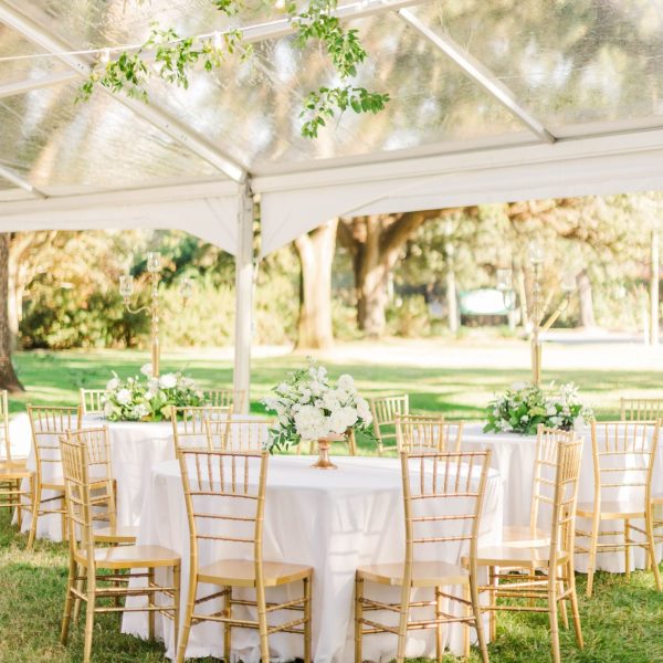 A vertical beautiful view of chairs around white tables at an outdoor wedding venue